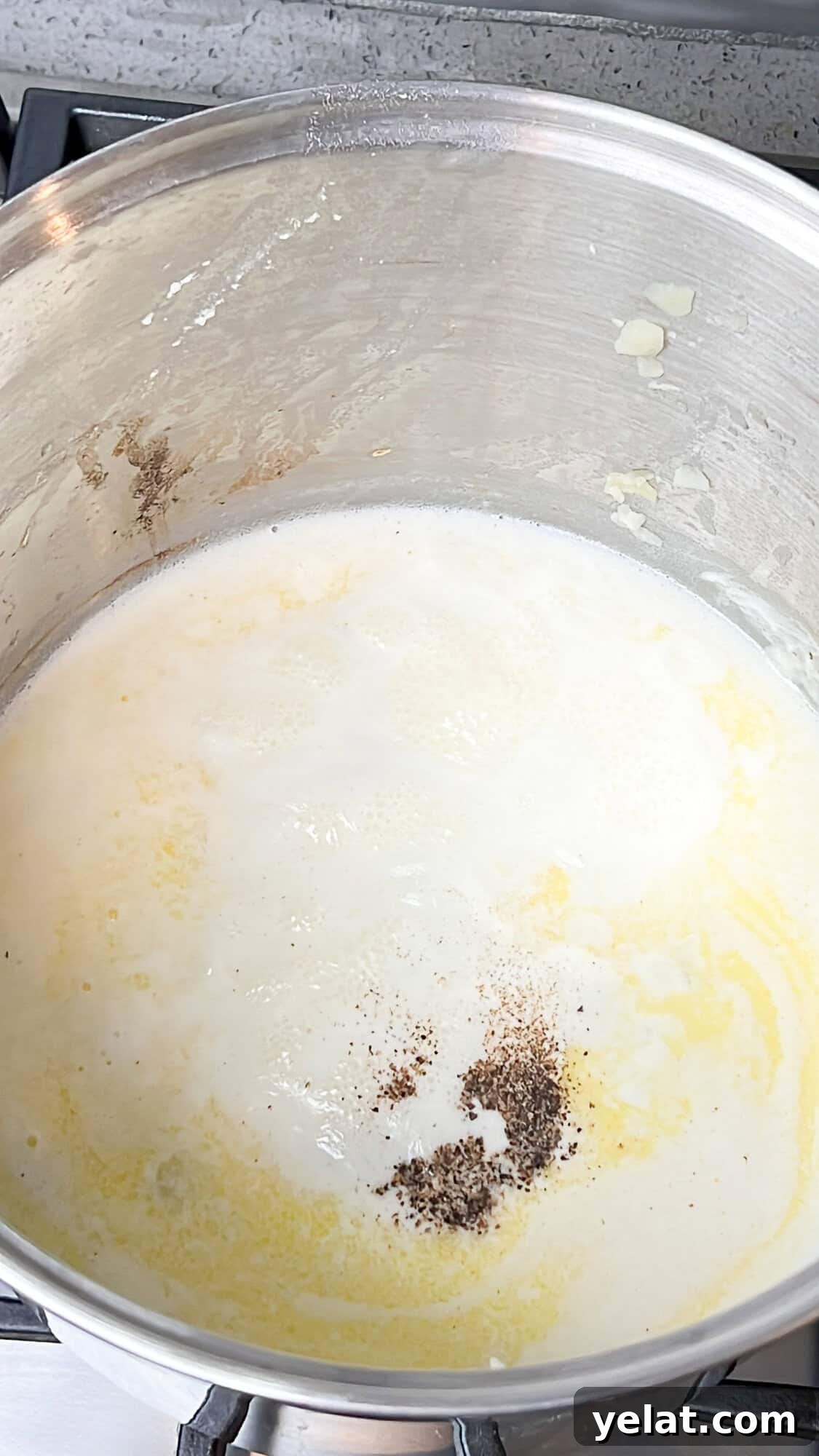 Cream in a pot simmering with black pepper