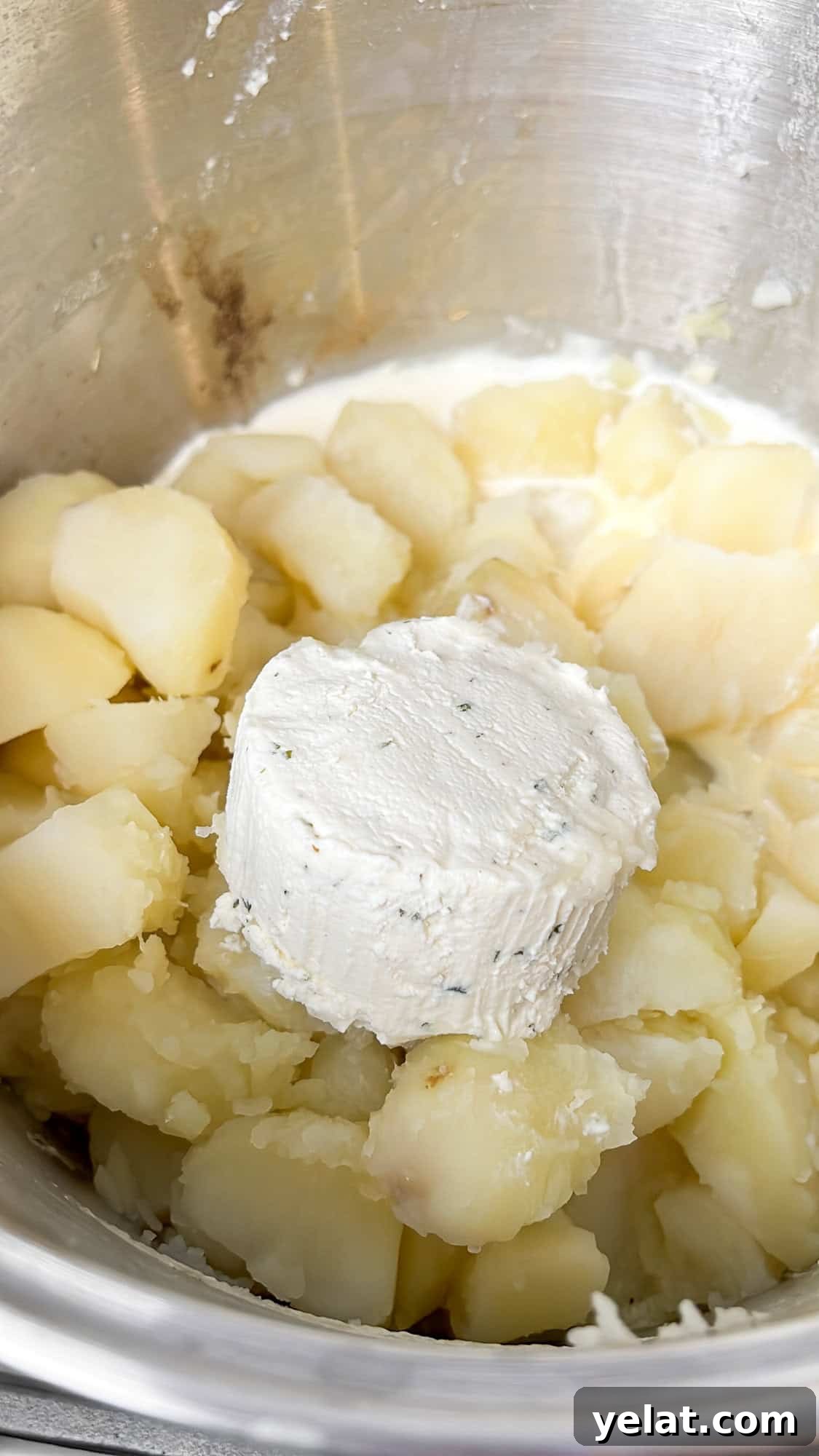 adding boursin cheese to the potatoes in a pot
