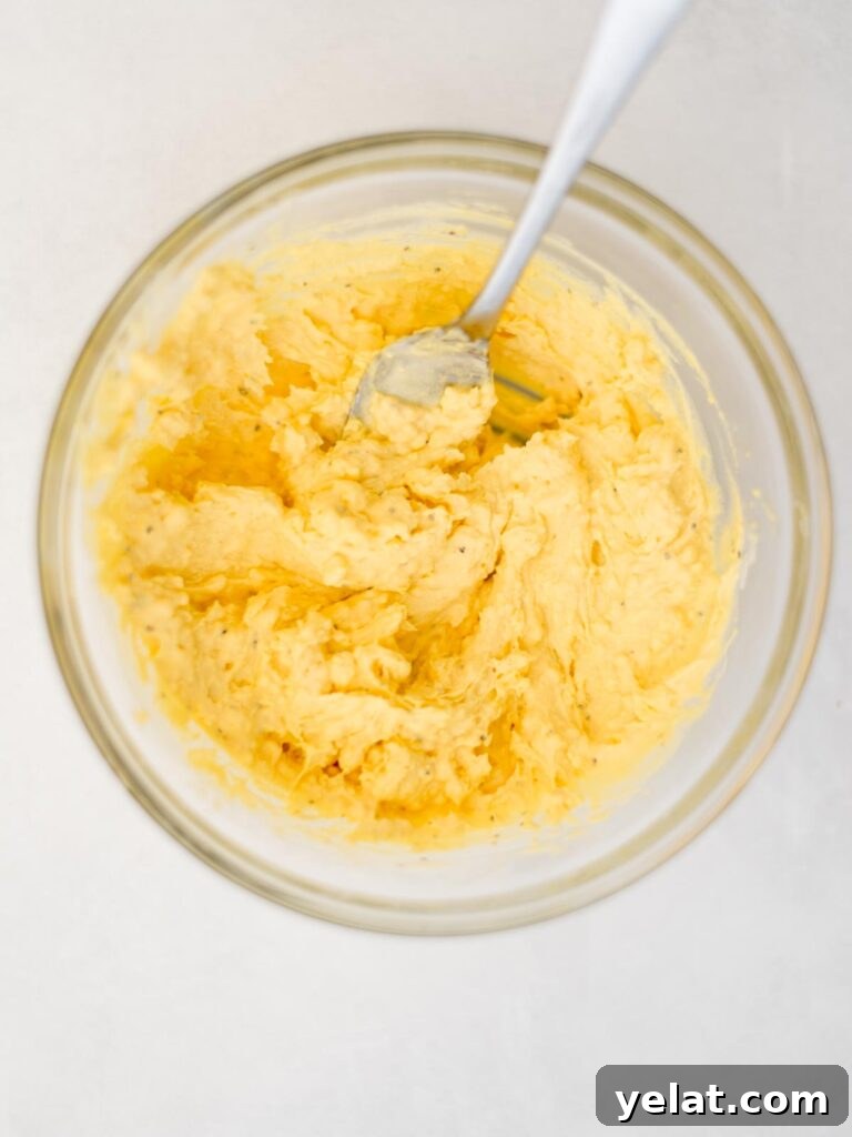 Creamy Deviled Eggs with Dijon Mustard and Fresh Herbs 7 Fork resting in a bowl of filling for deviled eggs.