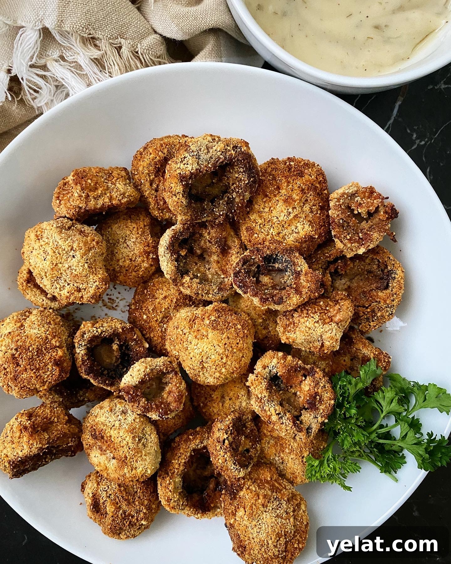 Crispy Keto Air-Fryer Fried Mushrooms: Low-Carb Snack Recipe 6 cooked air fryer fried mushrooms with a bowl of white dipping sauce