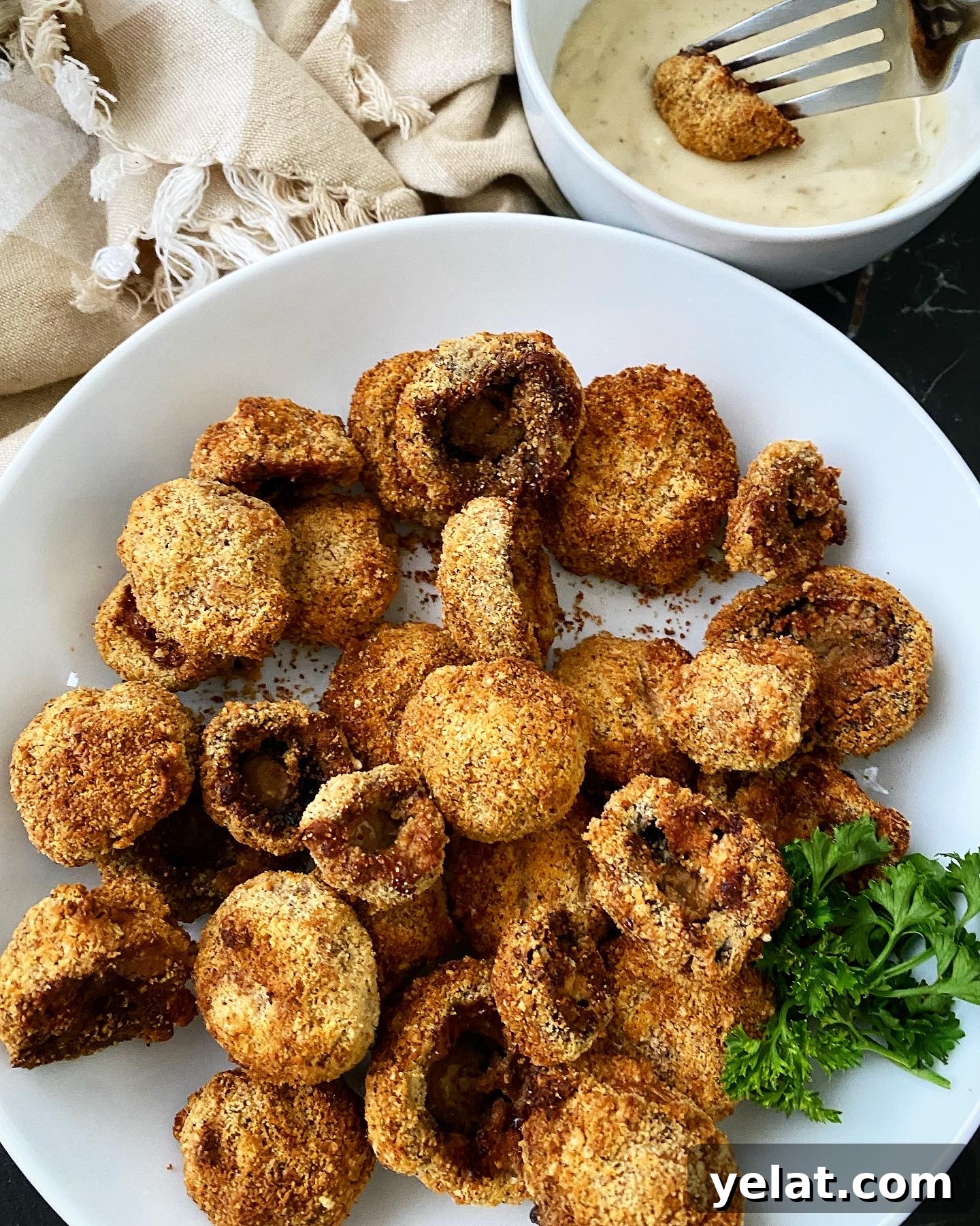 Crispy Keto Air-Fryer Fried Mushrooms: Low-Carb Snack Recipe 9 cooked air fryer fried mushrooms on a white plate with a mushroom dipped in ranch