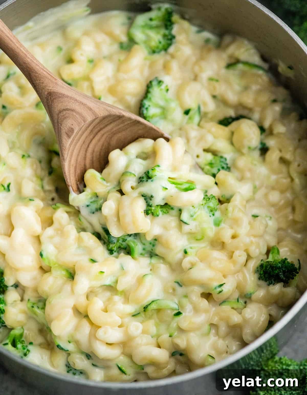 up close view of a wooden spoon scooping vegetable mac and cheese out of the pot