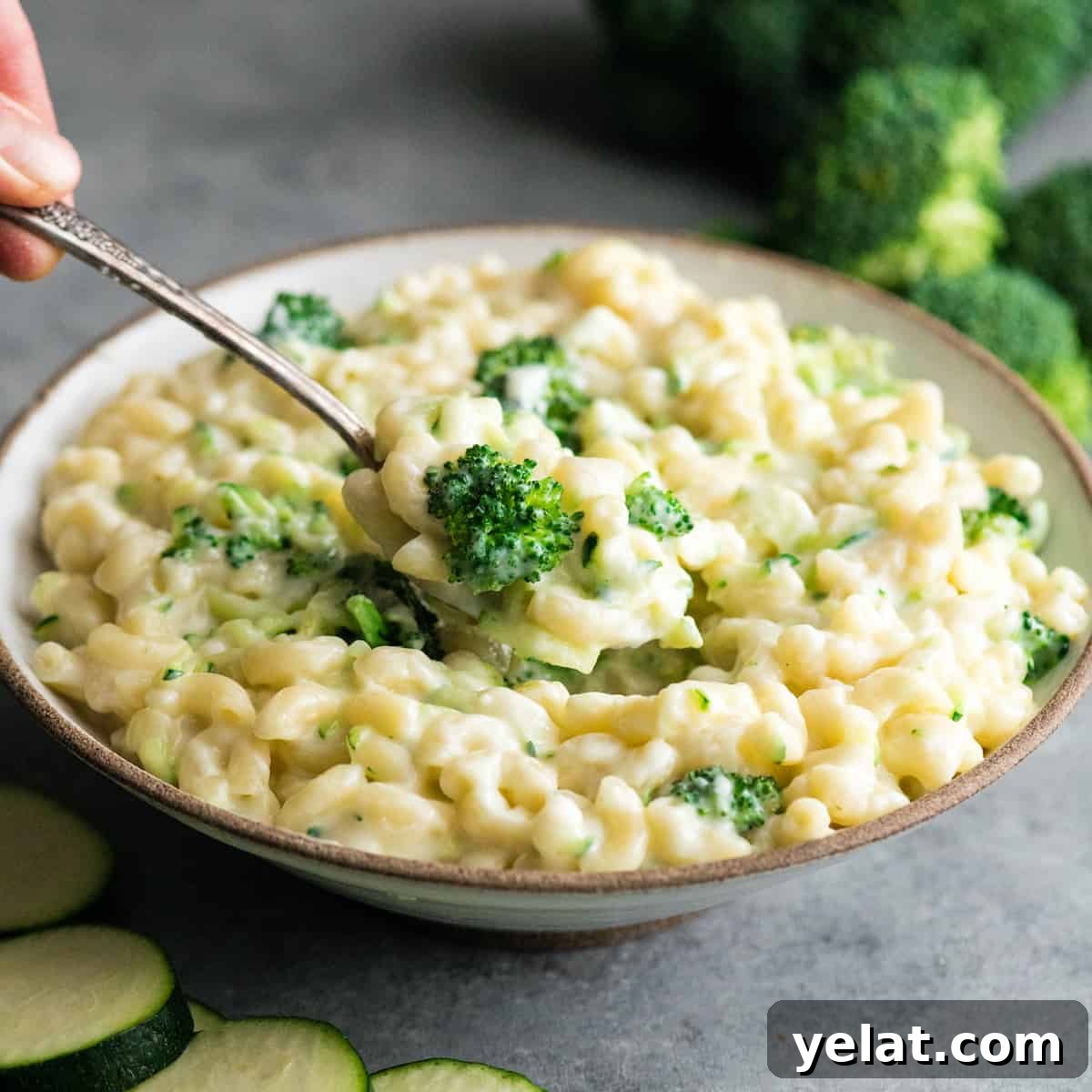 front view of a spoon taking a scoop of vegetable mac and cheese in a bowl