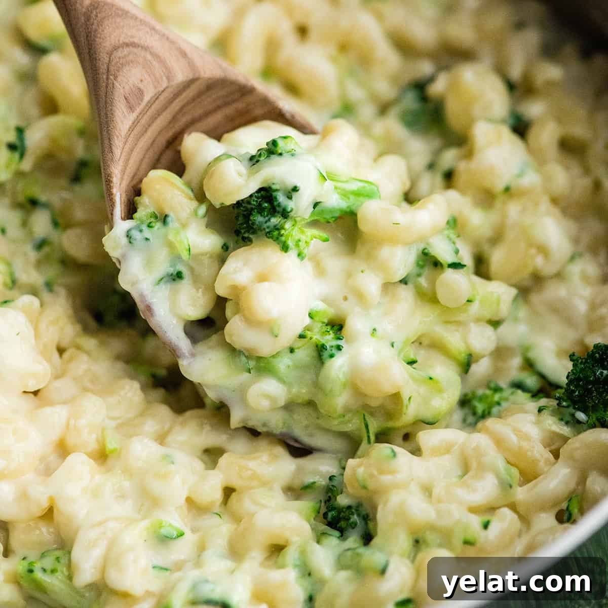 up close photo of veggie mac and cheese being scooped out of a pot with a wooden spoon