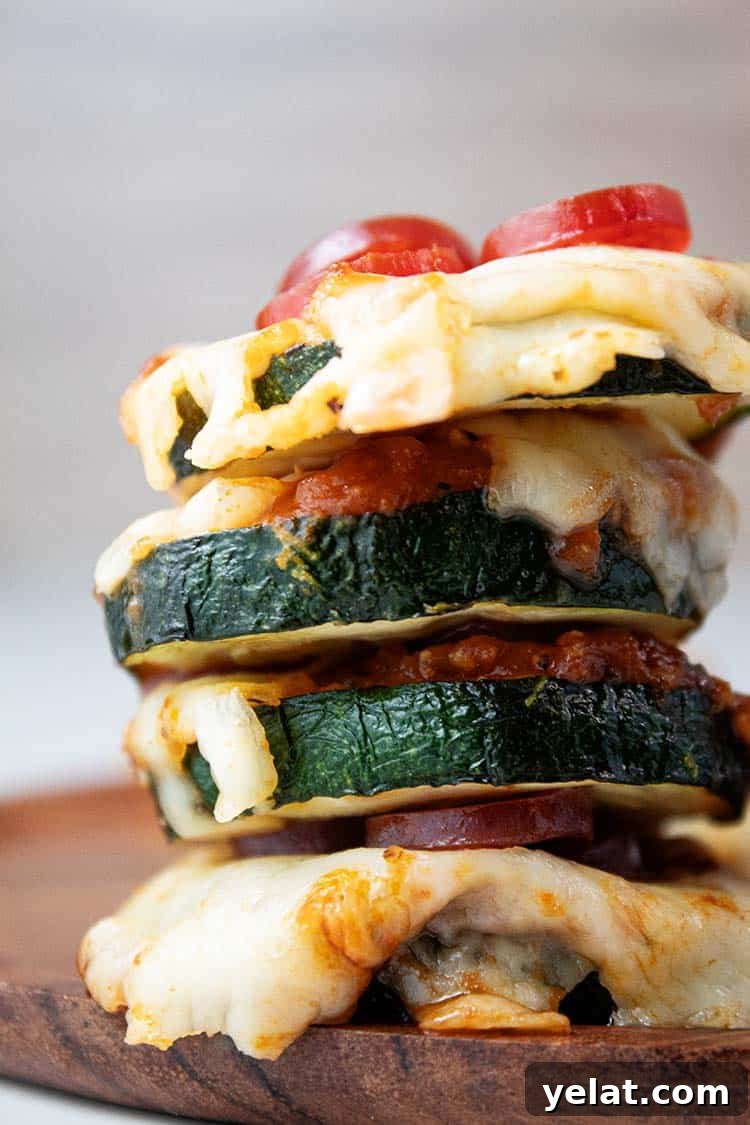 Zucchini Mini Pizzas: Bite-Sized Low-Carb Pizza Bites 11 stack of zucchini pizza bites topped with sauce, mozzarella cheese, and mini pepperoni air fried and ready to be served on a wooden serving plate