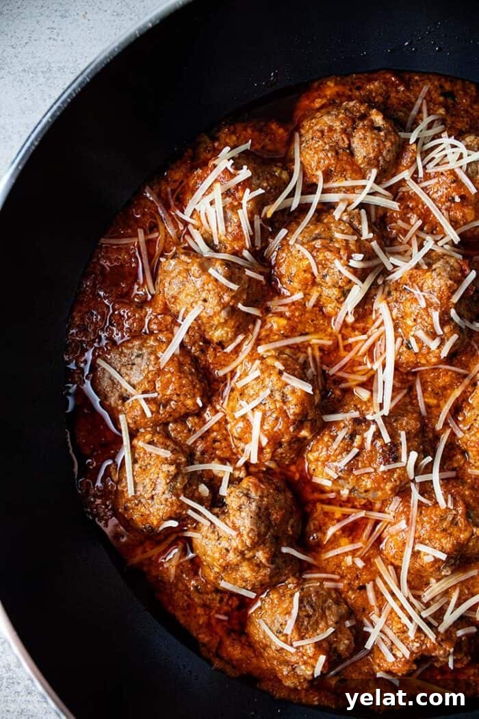 Zucchini Mini Pizzas: Bite-Sized Low-Carb Pizza Bites 13 overhead view of keto meatballs with marinara sauce topped with shredded parmesan cheese in a black skillet