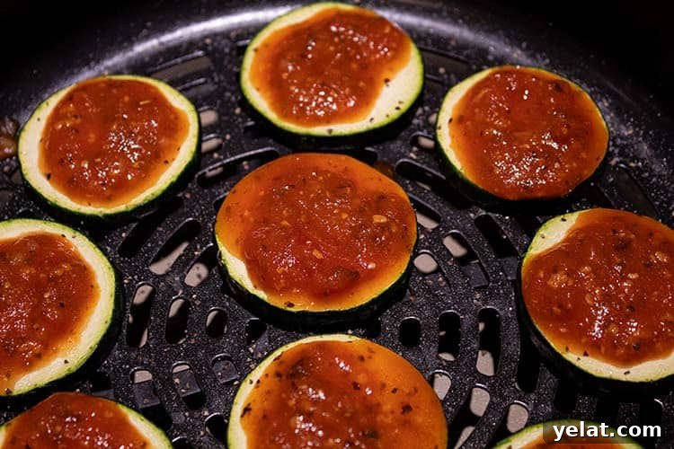 Zucchini Mini Pizzas: Bite-Sized Low-Carb Pizza Bites 5 overhead view of air fried sliced zucchini with marinara sauce spread on the top of each one