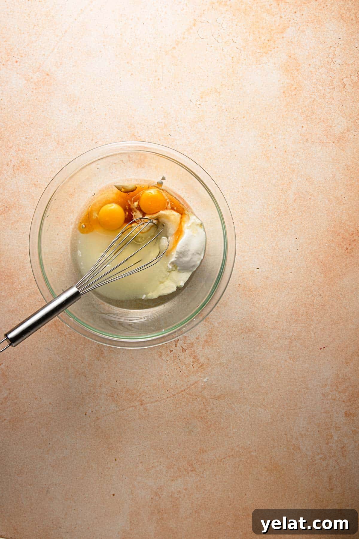 Baklava Muffins: Mediterranean Dessert with Honey, Nuts & Phyllo 5 A bowl with egg, oil and sour cream with a whisk.