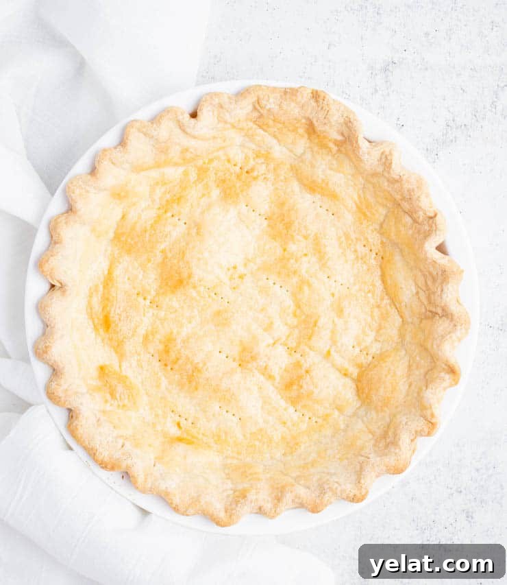 Flaky Pie Crust Recipe: A Complete Step-by-Step Guide 10 Pie crust baked to a golden brown with crimped edges in a white pie dish.