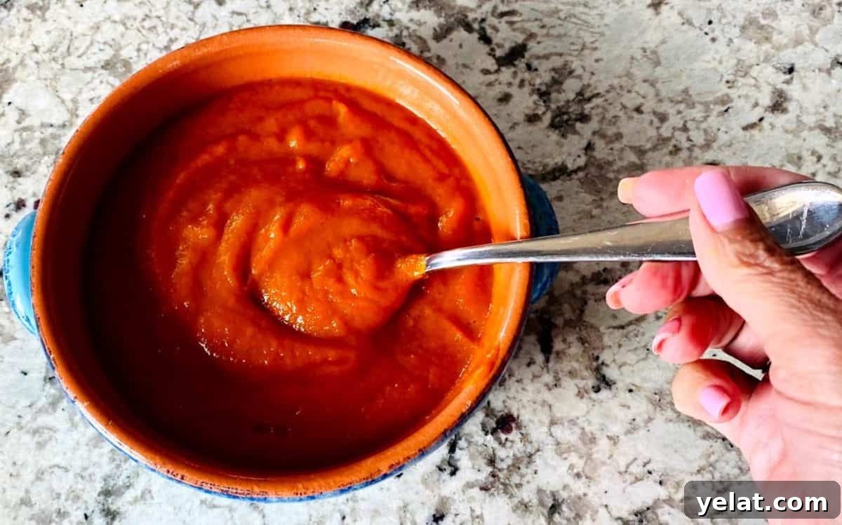 Creamy Roasted Red Pepper Pasta with Parmesan and Basil 9 red pepper pasta sauce in a bowl on the counter with a spoon in it.