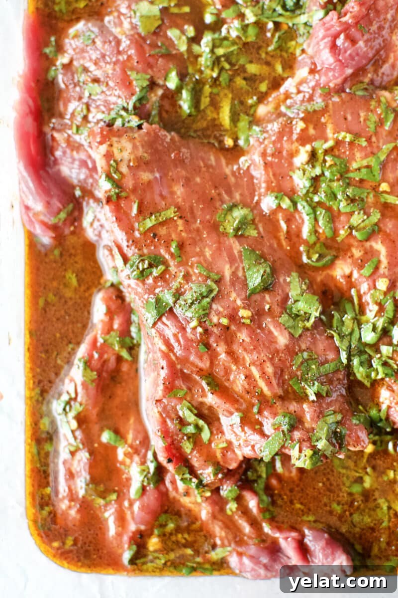 Carne Asada Marinade for Beef Fajitas and Tacos 7 Beef Loin Flap Meat Steak marinating in a pan.