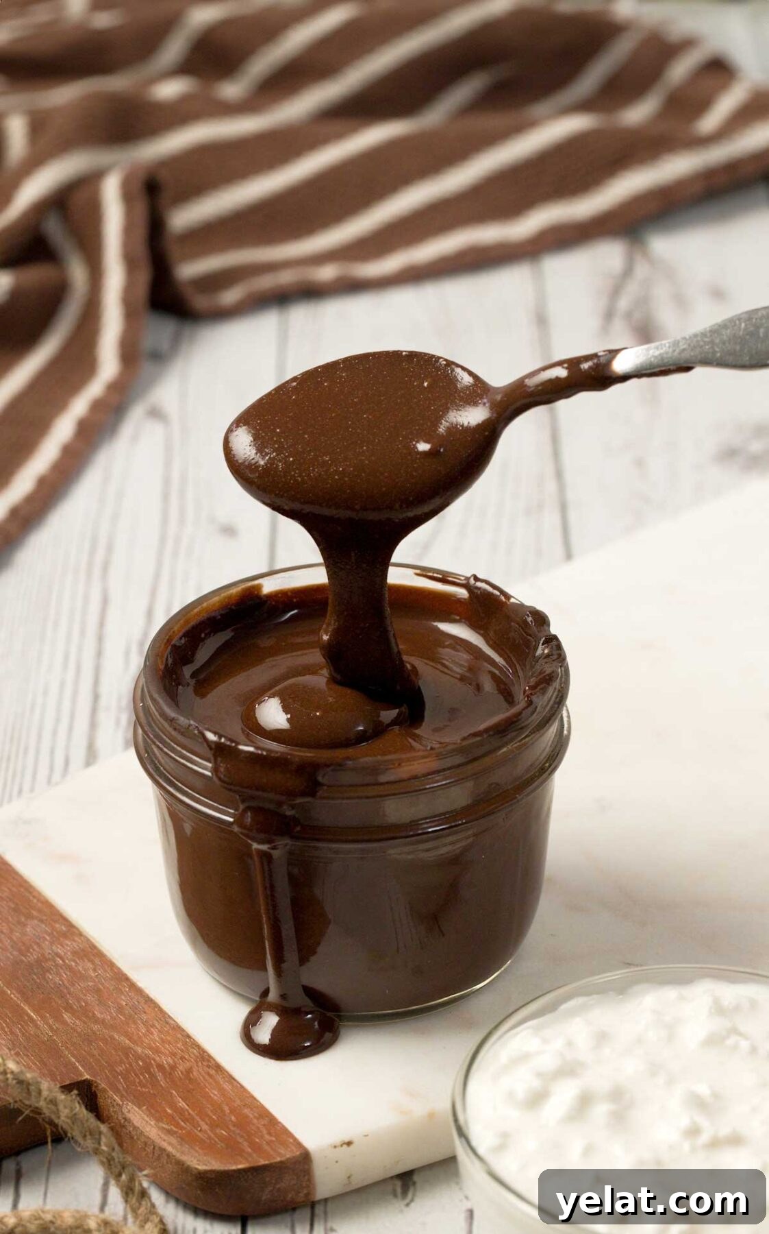 Light Protein Cottage Cheese with Chocolate Sauce Recipe 7 A spoon dripping protein cottage cheese chocolate sauce in a mason jar.