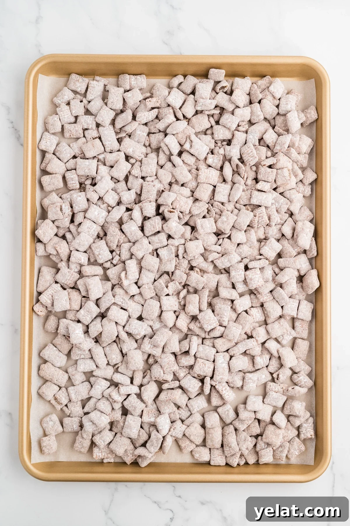 A sheet pan filled with homemade muddy buddies snack mix.