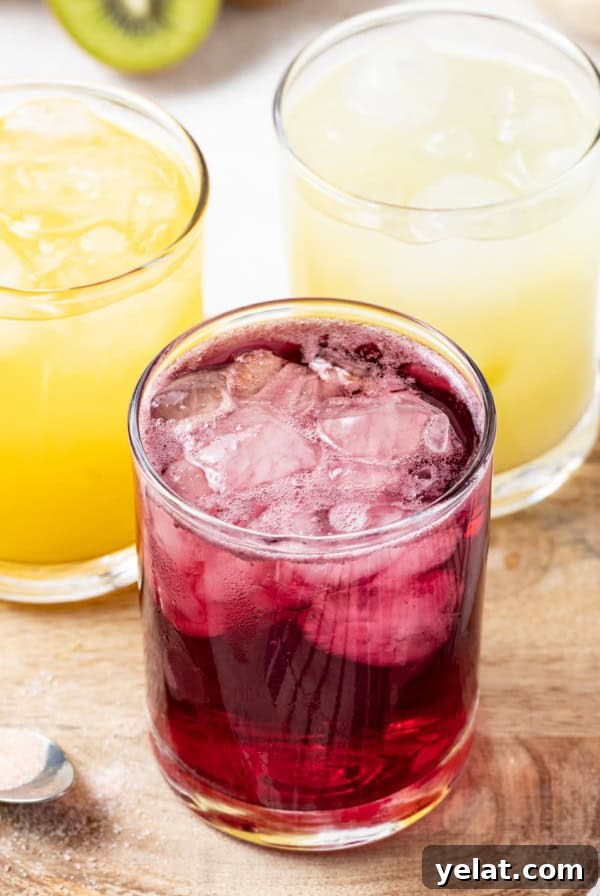 Pomegranate Virgin Sangria Recipe — Refreshing Party Drink 11 3 flavors of homemade gatorade in glasses on a wood table next to a spoon with salt.