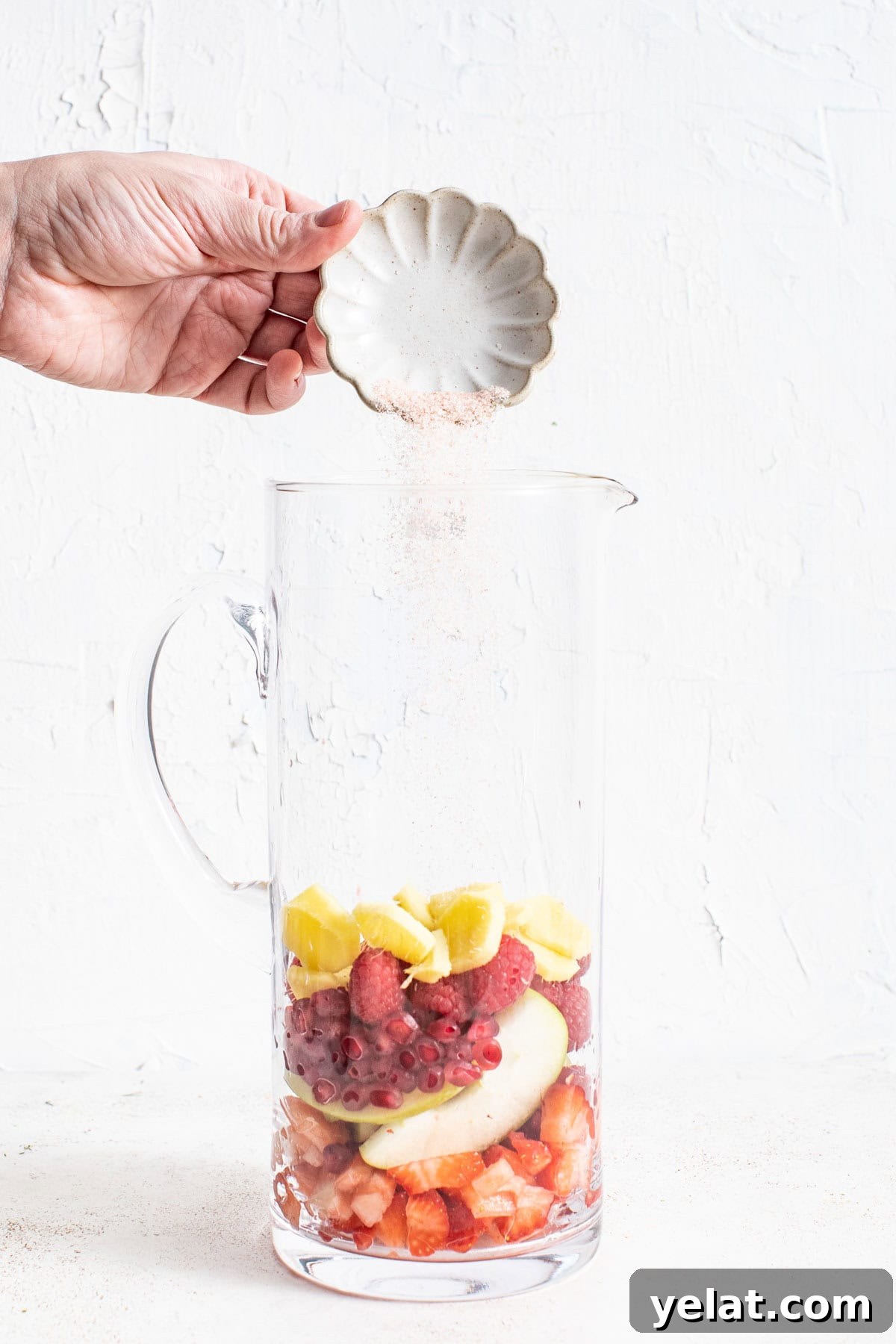 Pomegranate Virgin Sangria Recipe — Refreshing Party Drink 4 Pouring salt into the pomegranate mixture in a tall pitcher.
