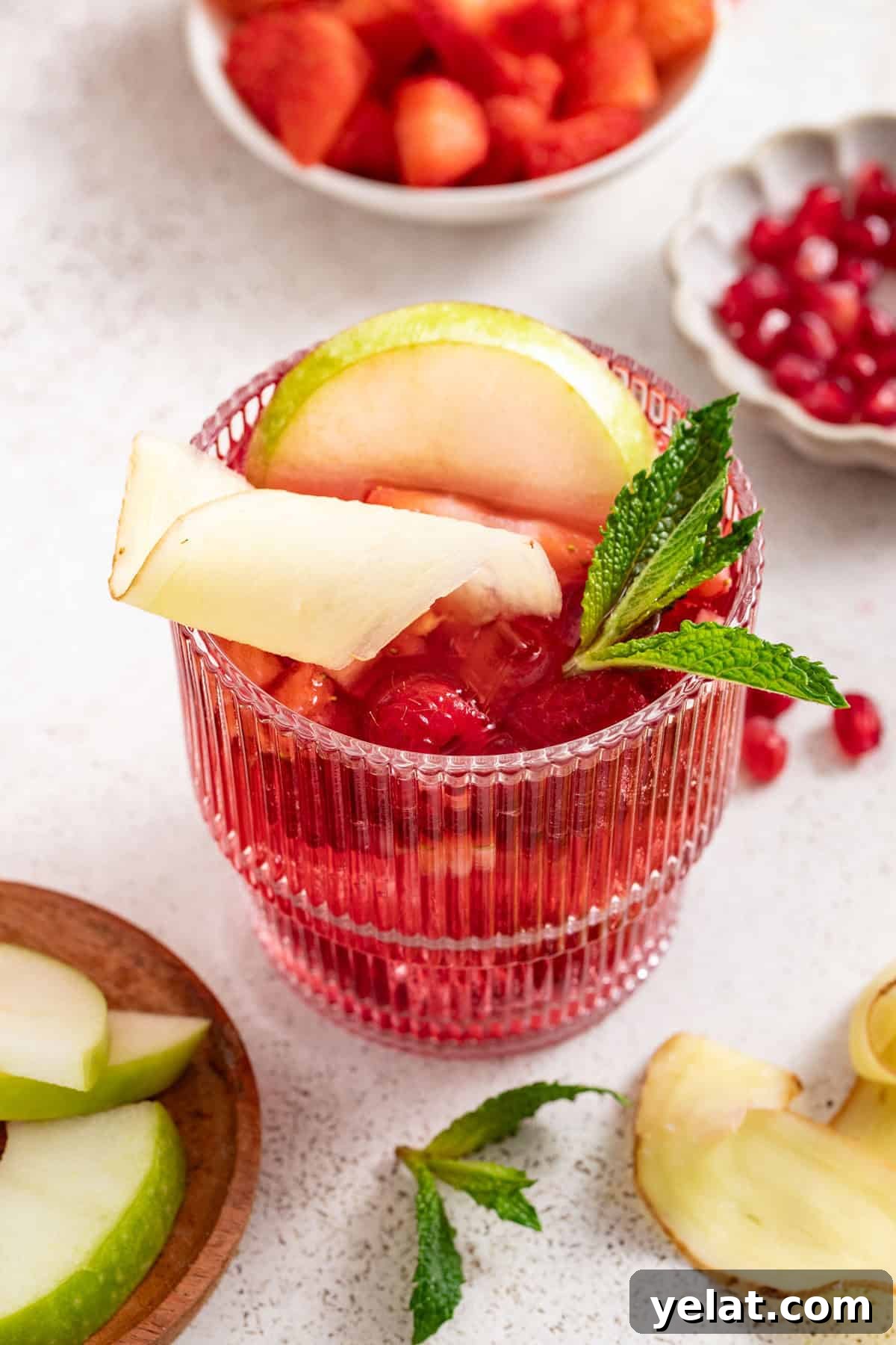 Pomegranate Virgin Sangria Recipe — Refreshing Party Drink 8 Close up of a red sangria without alcohol topped with apples, mint, and ginger.