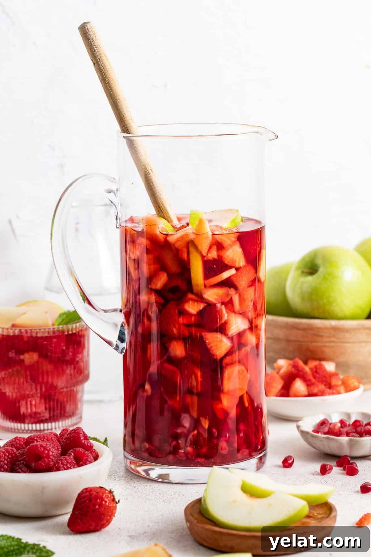 Pomegranate Virgin Sangria Recipe — Refreshing Party Drink 9 Pomegranate sangria without alcohol in a tall glass picture with a wood spoon.
