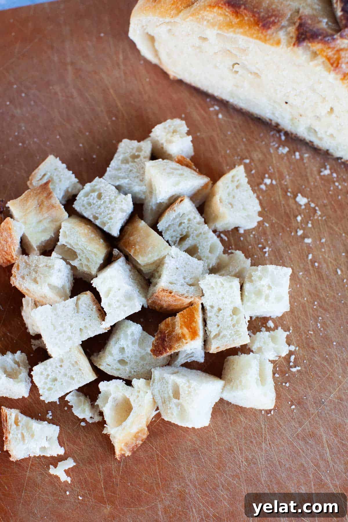 Crispy Homemade Croutons: Simple Recipe for Perfect Salads 5 Small square chunks of sourdough bread on a cutting board.