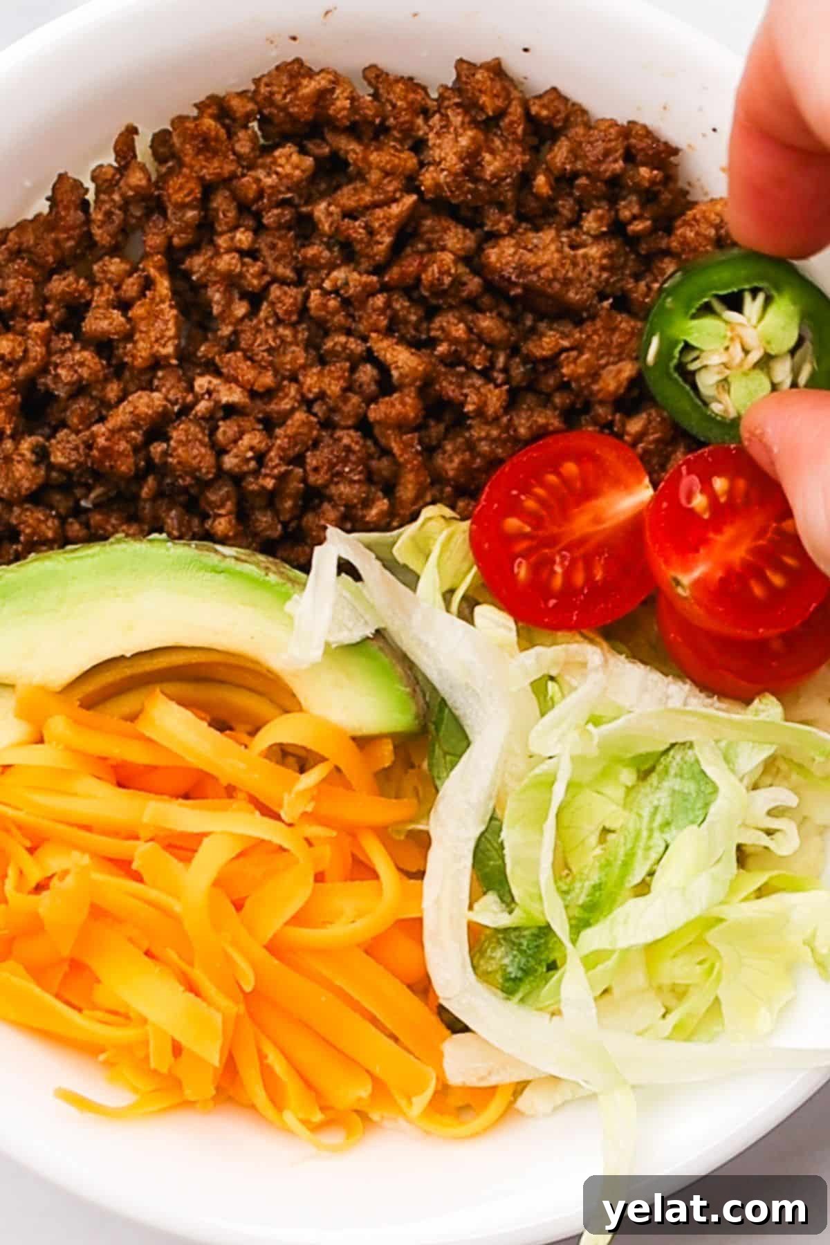 50 High-Protein Power Bowl Recipes for Every Meal 6 Low carb taco bowl with seasoned ground beef, shredded cheddar cheese, sliced avocado, shredded lettuce, cherry tomatoes, and fresh jalapeño slices