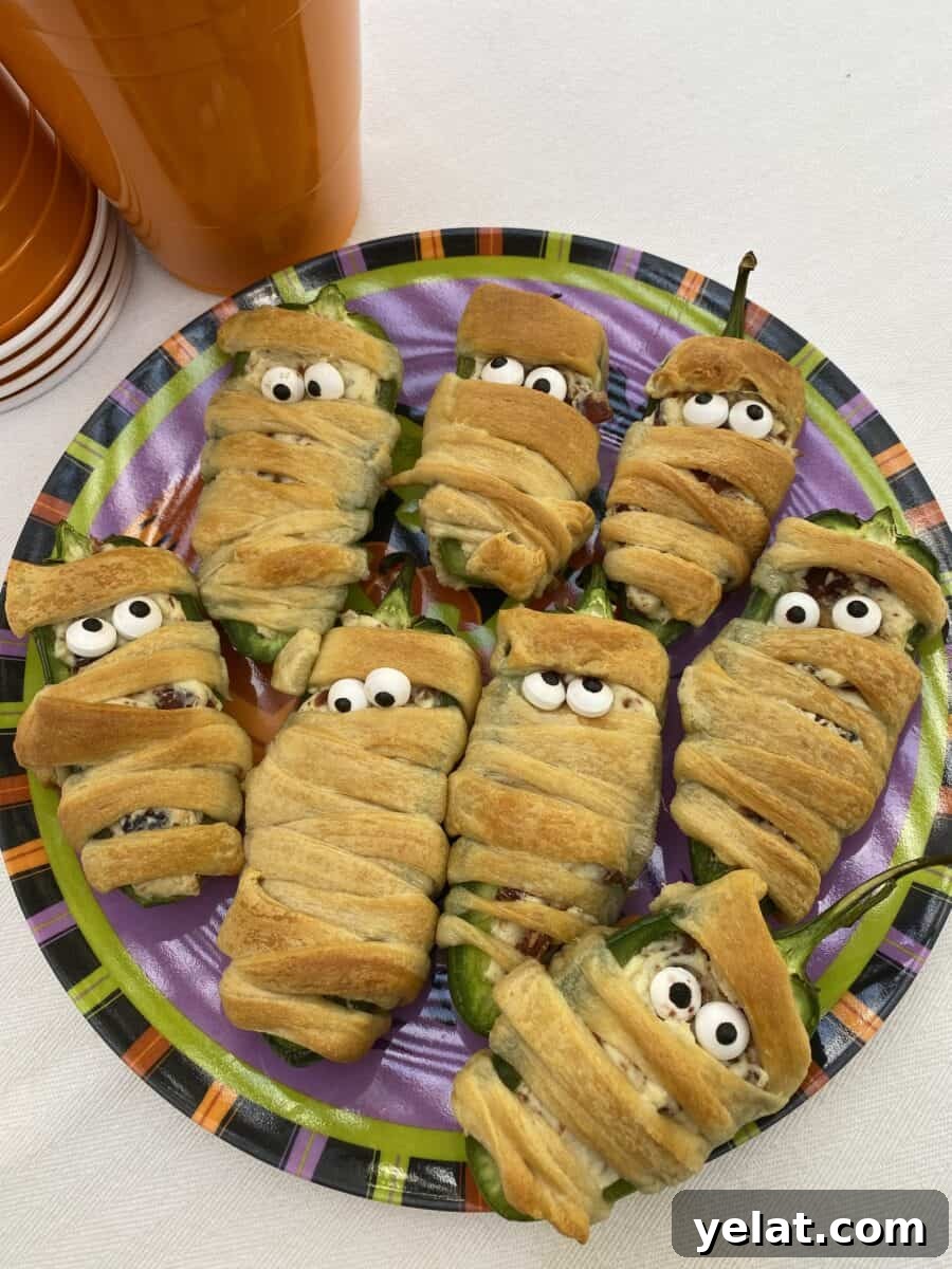Jalapeño Bacon Mummies: Spicy Stuffed Appetizer for Parties 5 A plate with eight wrapped jalapeño poppers wrapped in dough.