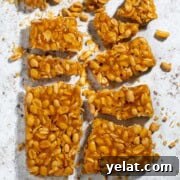 Homemade Peanut Brittle Without Corn Syrup — Crunchy Recipe 6 Peanut brittle without corn syrup broken into pieces on a white background.