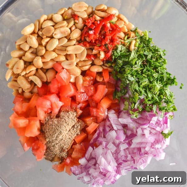 Spicy Peanut Chaat Recipe: Indian Masala Peanuts in Minutes 6 A glass bowl with peanuts, cilantro, red onion and tomatoes