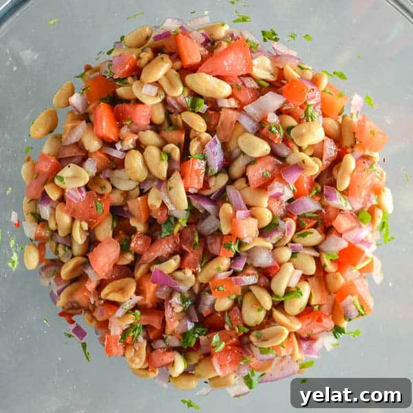 Spicy Peanut Chaat Recipe: Indian Masala Peanuts in Minutes 7 A glass bowl with a mixture of peanuts, tomatoes, fresh cilantro and red onion