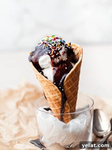 a gluten free waffle cone topped with vanilla ice cream and homemade fudge sauce