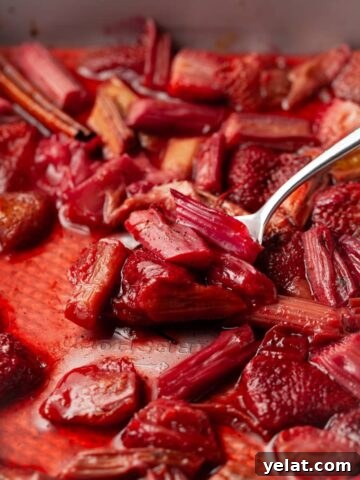 roasted strawberry rhubarb compote on a spoon in a baking dish