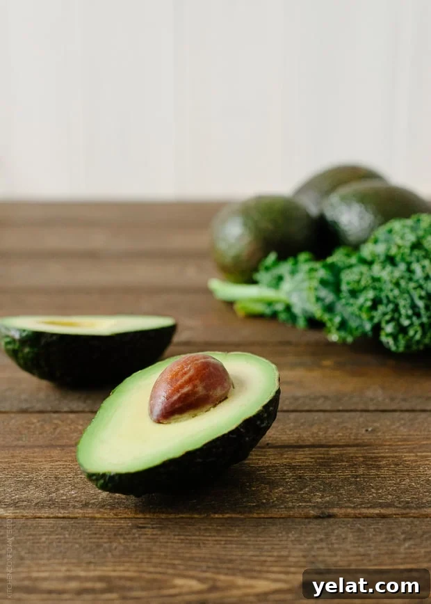 Avocado Kale Superfood Smoothie ingredients: avocado cut in half and kale leaves
