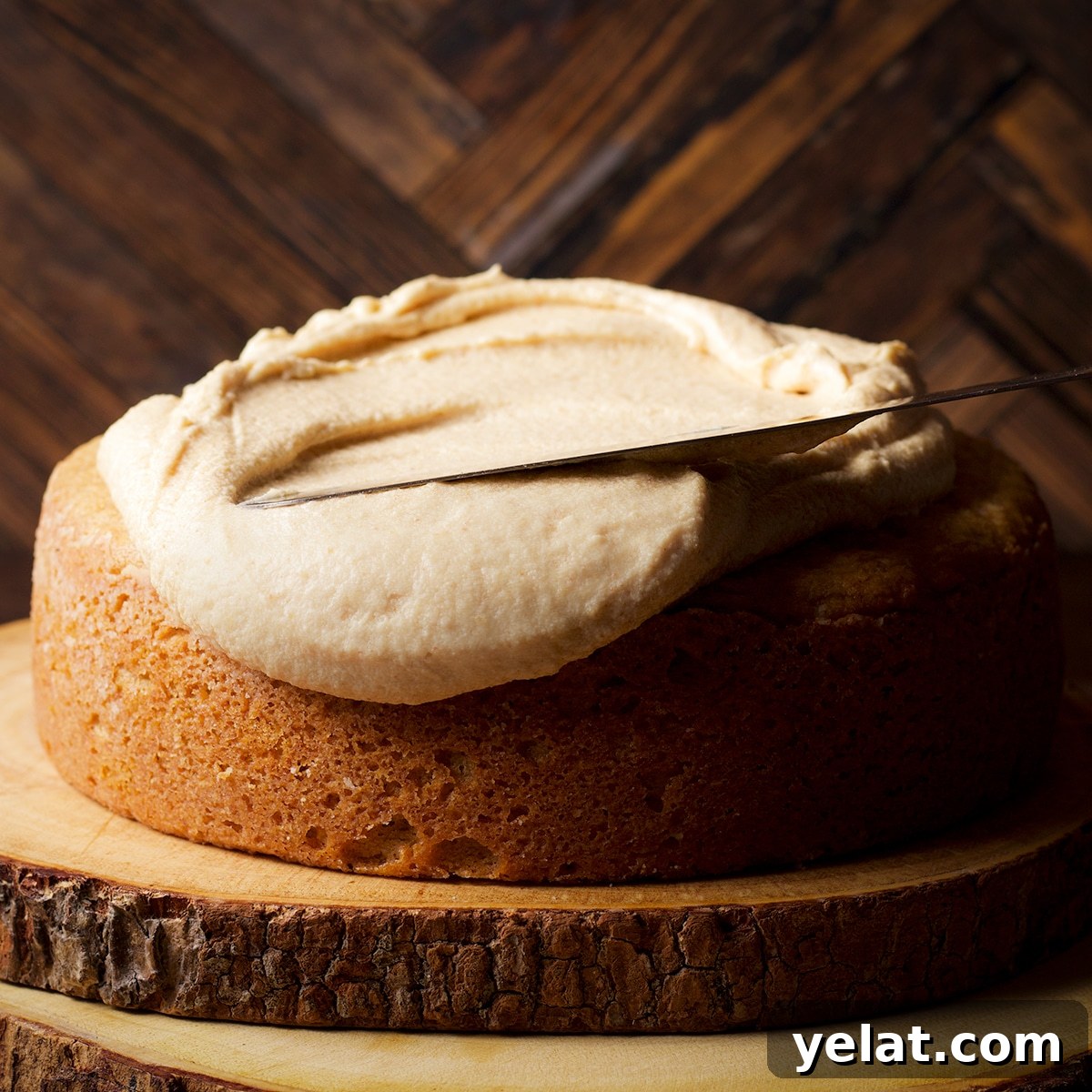 Using a flat icing spatula to spread maple miso brown butter frosting over a round one layer cake.