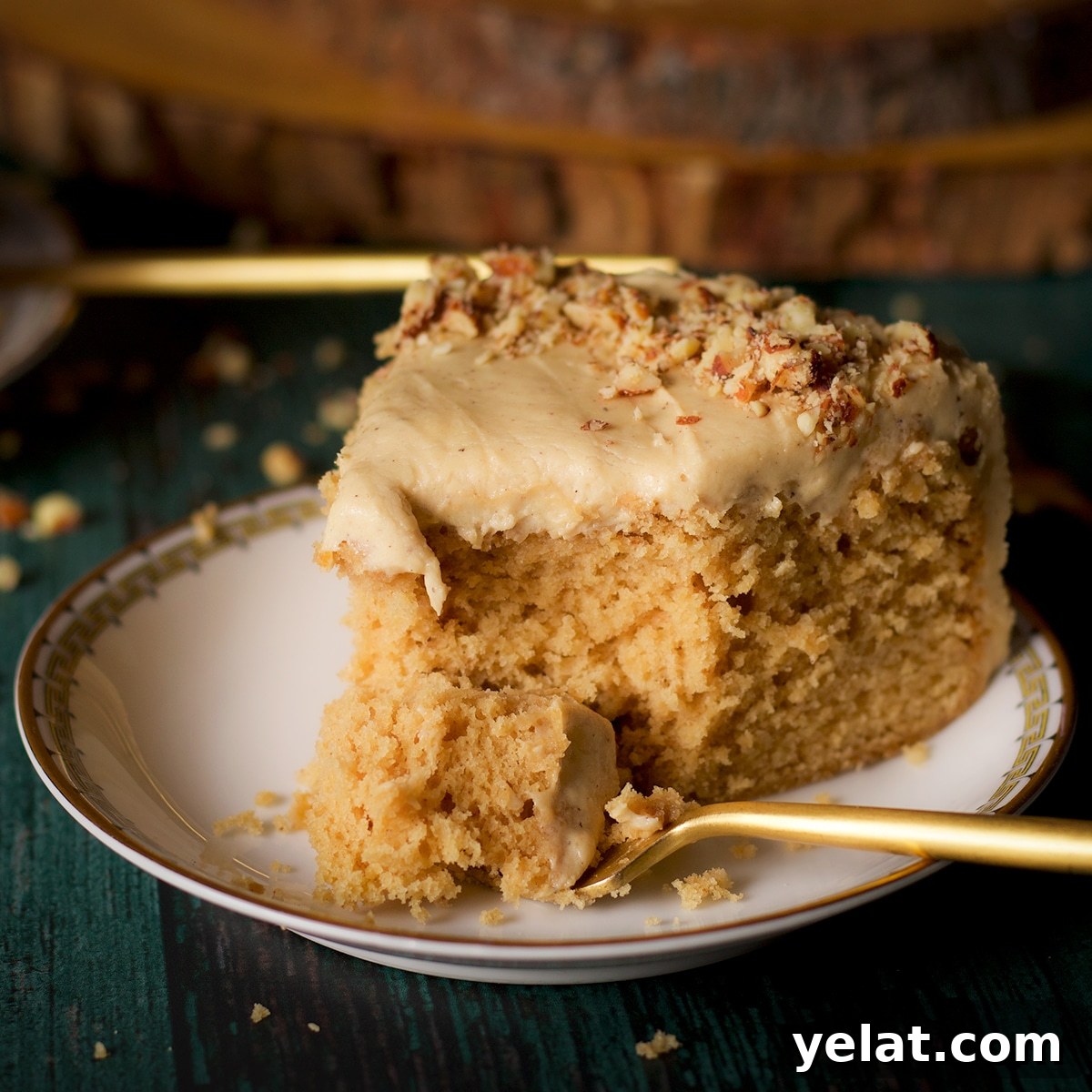 A slice of brown butter cake with maple miso brown butter frosting on a plate with a fork.