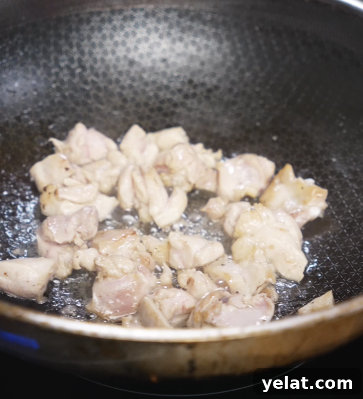 Garlic Butter Chicken Recipe with Crispy Pan-Seared Thighs 5 Cubes of chicken thigh cook in a hot pan until browned and golden, forming the protein base of the garlic butter chicken bowl.