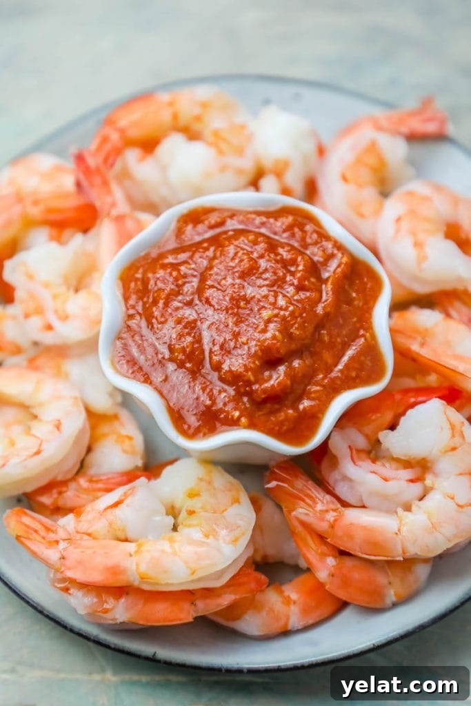 cooked shrimp cocktail on a plate around a cup of bright red cocktail sauce