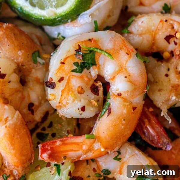Close-up of Cilantro Lime Sautéed Shrimp garnished with chopped herbs, red pepper flakes, and lime wedges.