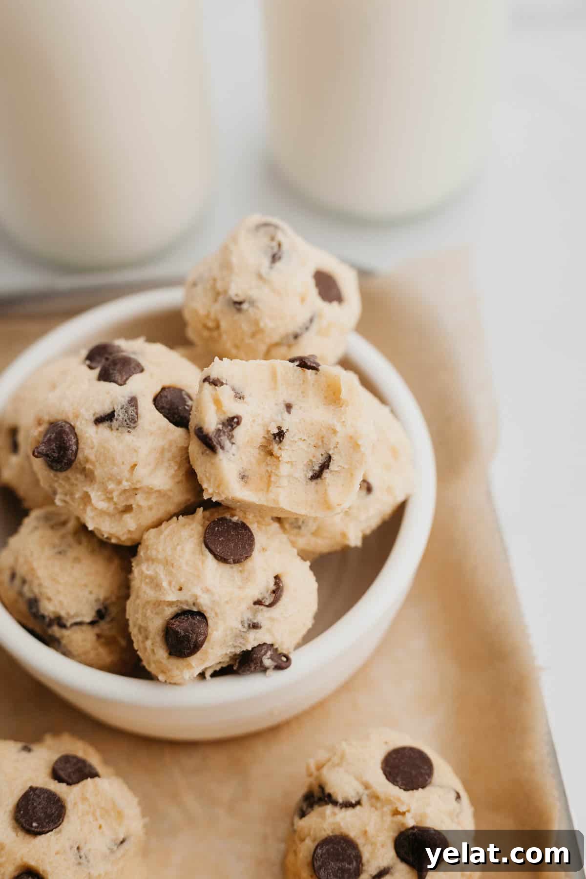 No-Bake Chocolate Chip Cookie Dough Bites for Snacking 2 no bake chocolate chip cookie dough bites in a small ceramic bowl.