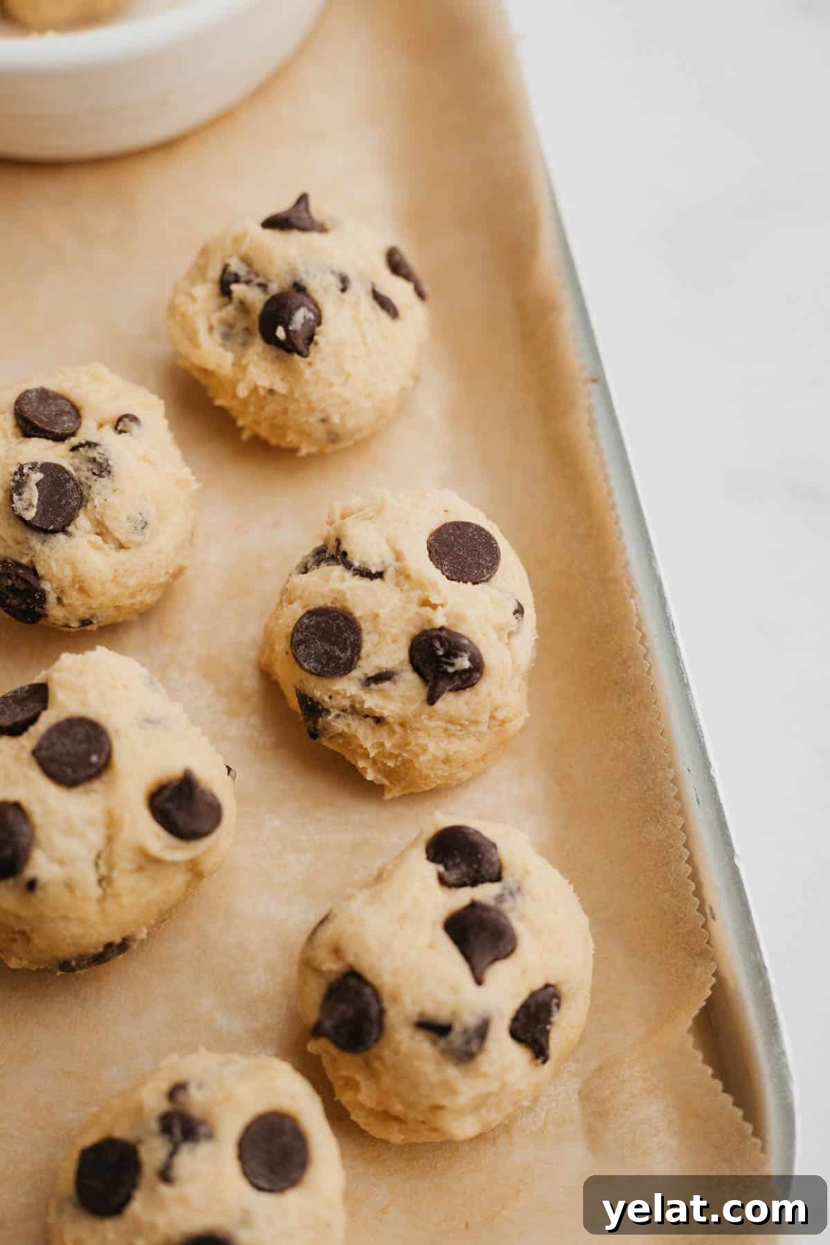 No-Bake Chocolate Chip Cookie Dough Bites for Snacking 6 chocolate chip cookie dough balls on parchment paper.