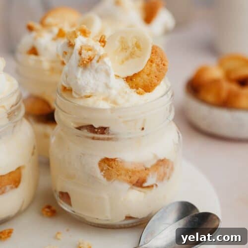 A close up of banana pudding in a jar on a marble surface.