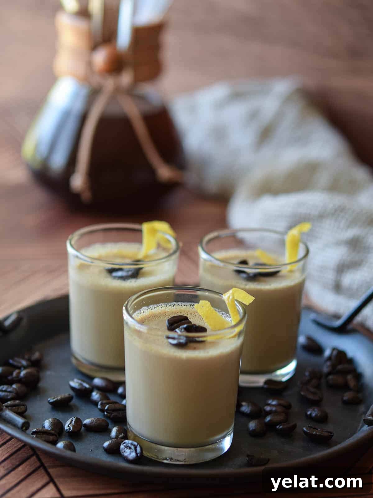 Espresso panna cotta in small glass jars with coffee beans and lemon rind twists.
