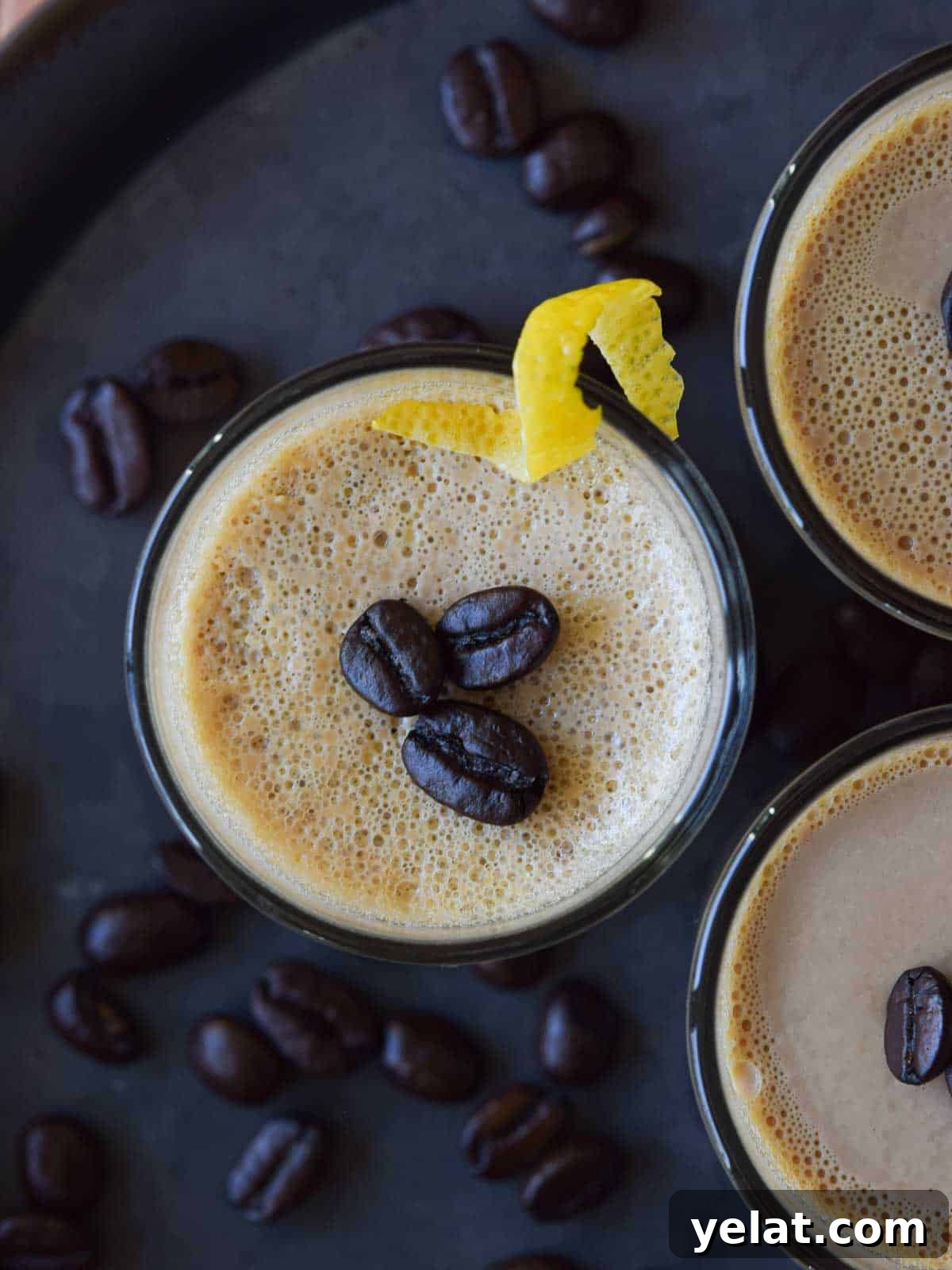 Overhead view of espresso coffee panna cotta topped with coffee beans and a lemon rind.