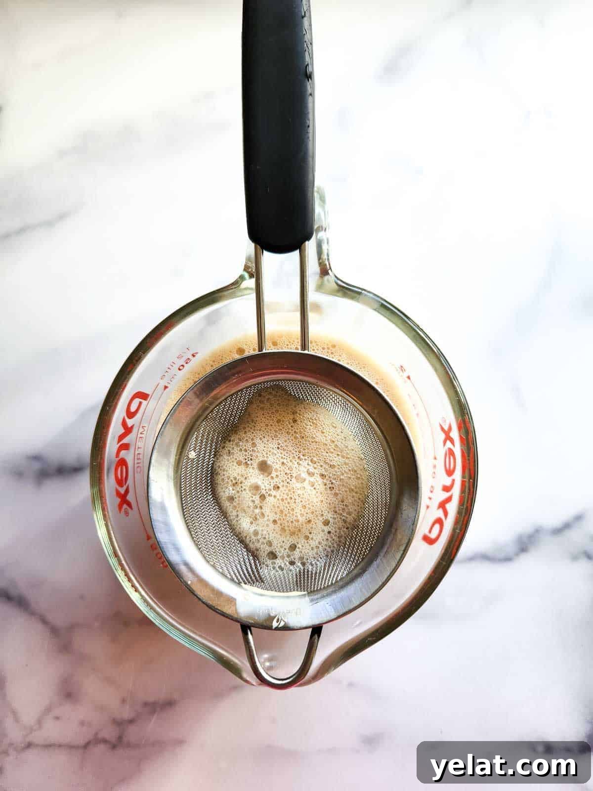Straining espresso panna cotta liquid into a cup.