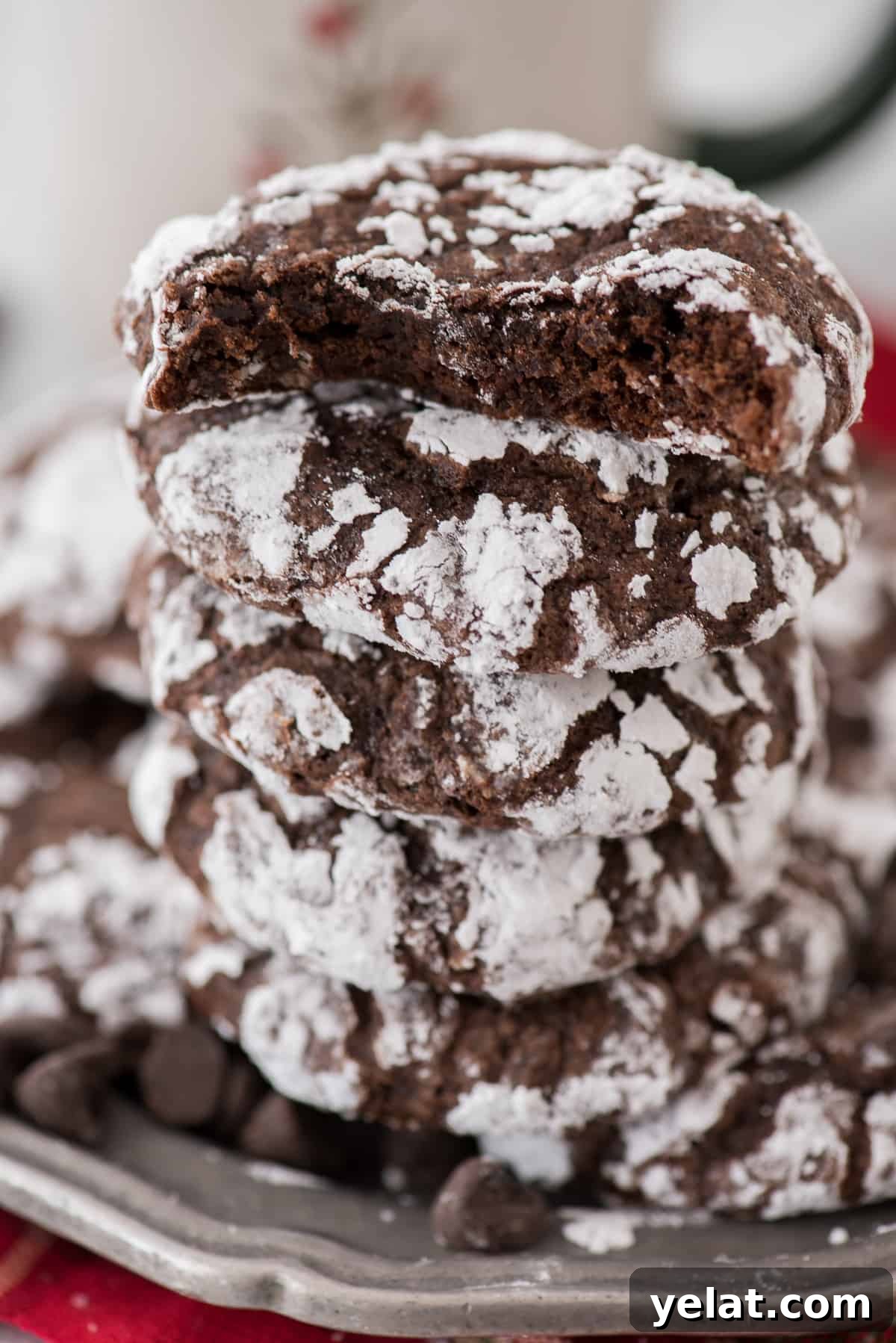 Chewy Chocolate Crinkle Cookies Recipe for Perfectly Soft Centers 9 chocolate crinkle cookies rolled in powdered sugar stacked on a metal plate