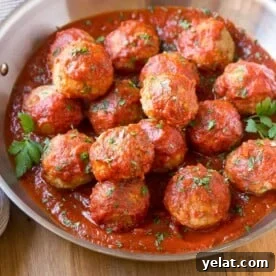 Italian Baked Turkey Meatballs with Herbed Tomato Sauce 8 turkey meatballs in a bowl with tomato sauce.