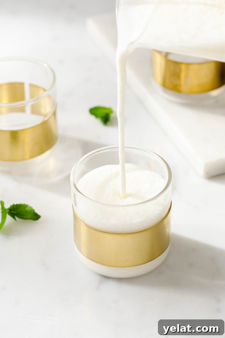 Authentic Sweet Lassi Recipe: Creamy Indian Yogurt Drink Guide 11 Pouring Yogurt Lassi into a clear, copper-lined glass.