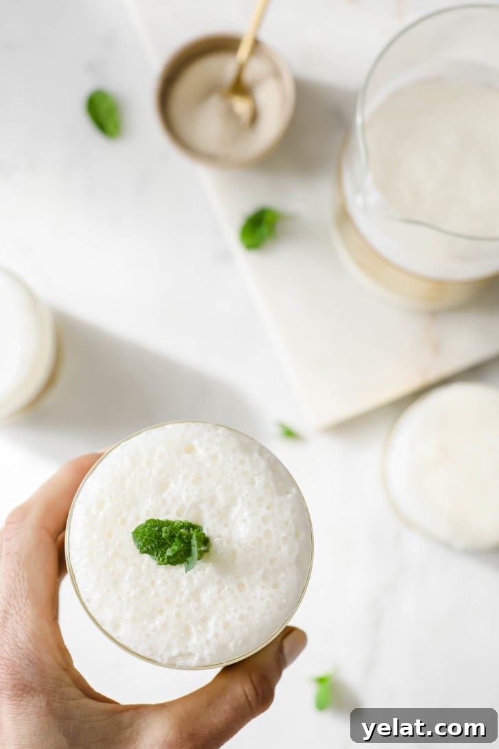 Authentic Sweet Lassi Recipe: Creamy Indian Yogurt Drink Guide 13 Holding a glass of frothy lassi garnished with mint.
