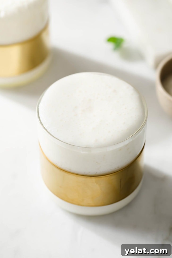 Authentic Sweet Lassi Recipe: Creamy Indian Yogurt Drink Guide 6 Frothy Lassi in a clear modern glass.