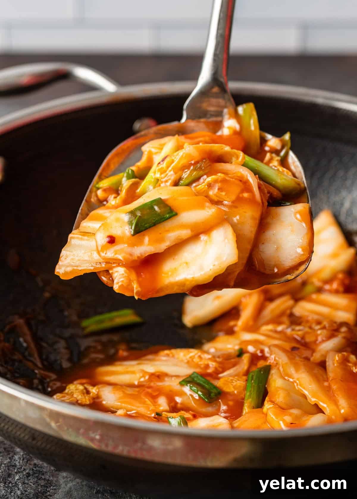 closeup: a large spoon lifting up a serving of my cabbage stir fry recipe out of a wok