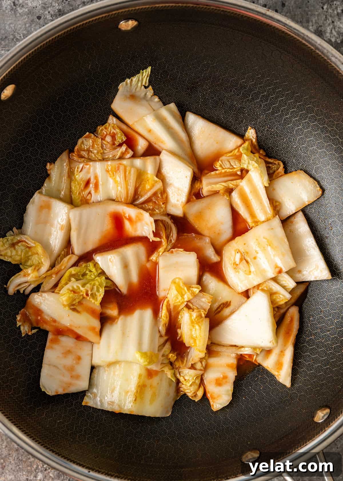overhead process shot: cabbage cooking with sauces in a wok