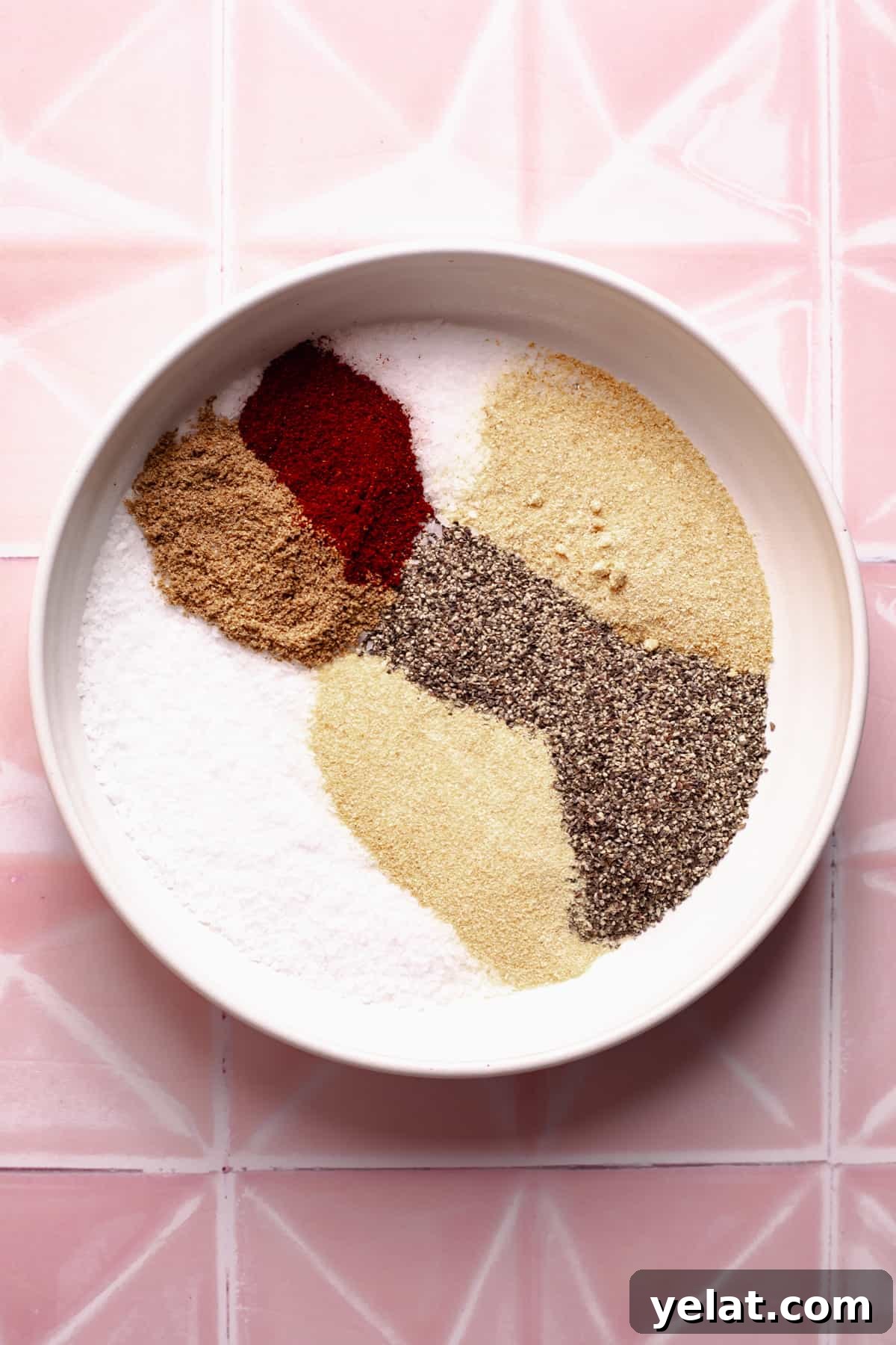 Ultimate Texas-Style Brisket Rub Recipe for Smoky Flavor 4 Spices in a white bowl on pink tile.