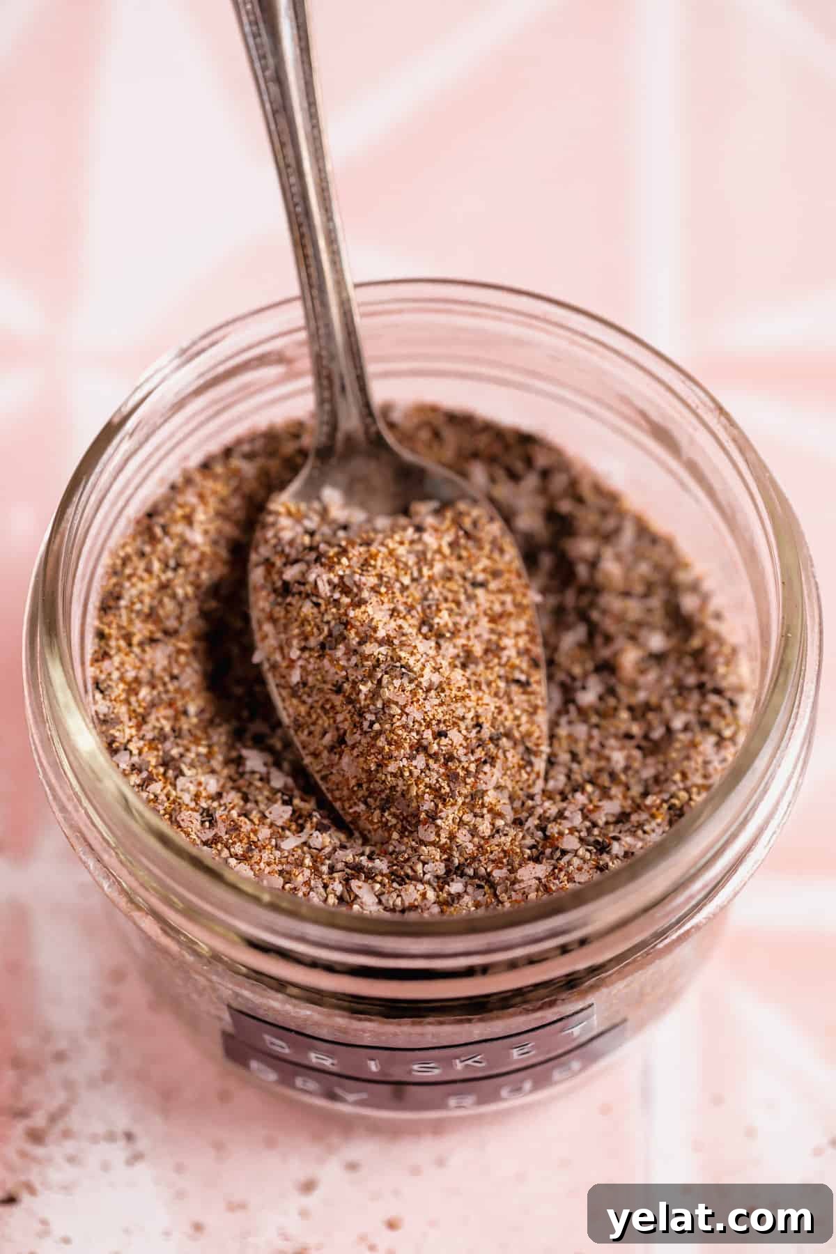 Ultimate Texas-Style Brisket Rub Recipe for Smoky Flavor 9 Spoon scooping up brisket rub from a glass jar.